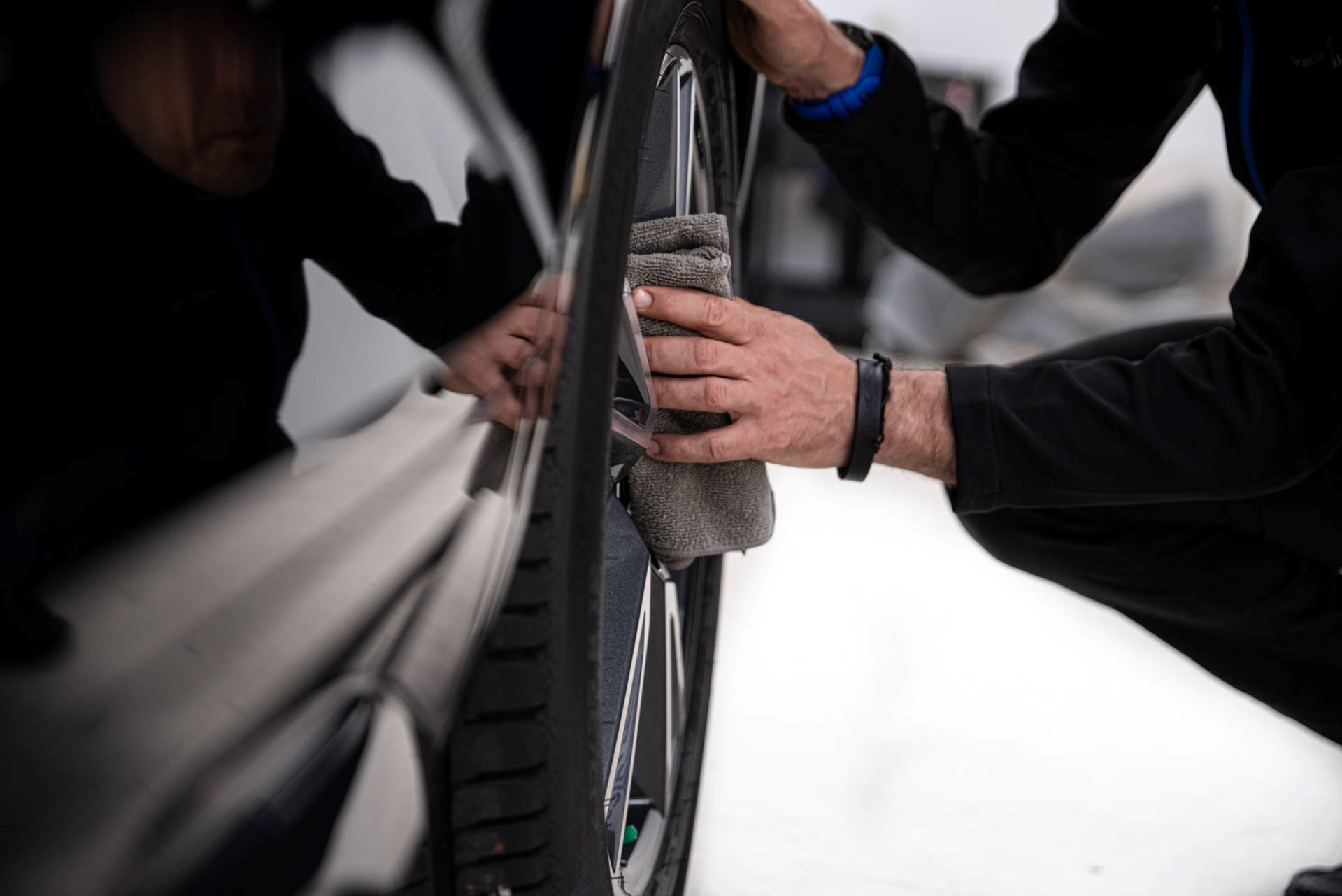 Man cleaning wheel of car with cloth