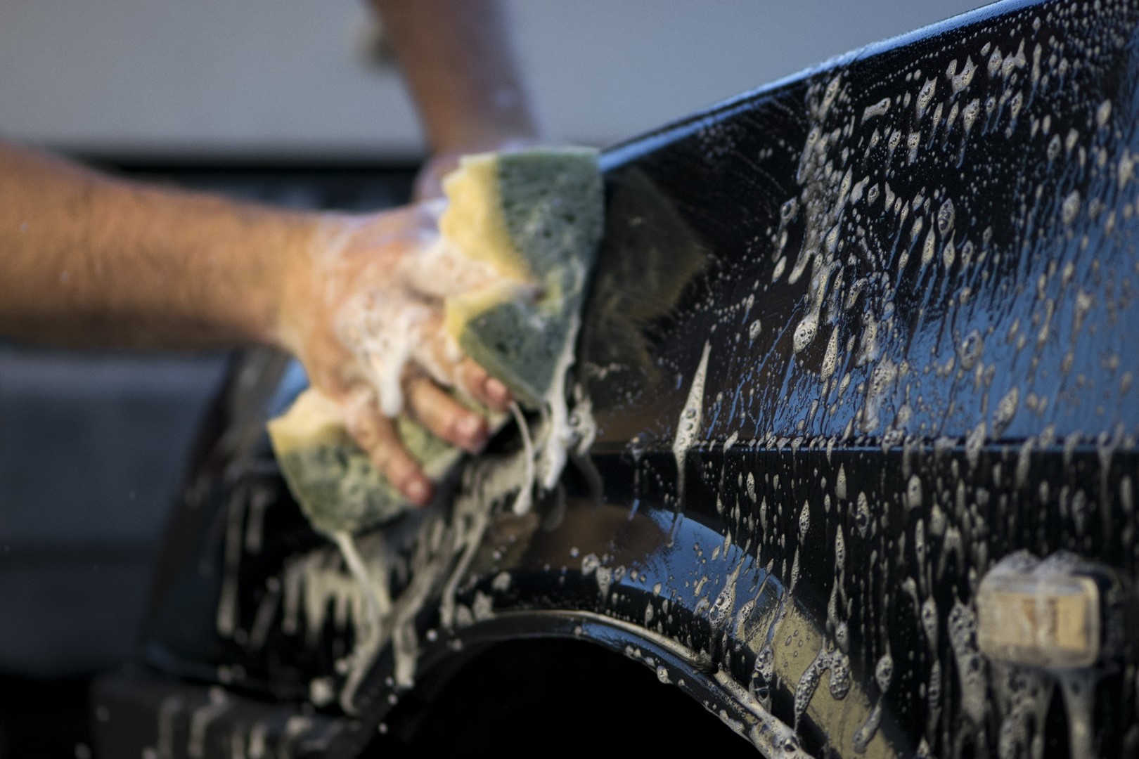 Person washing their car with a sponge